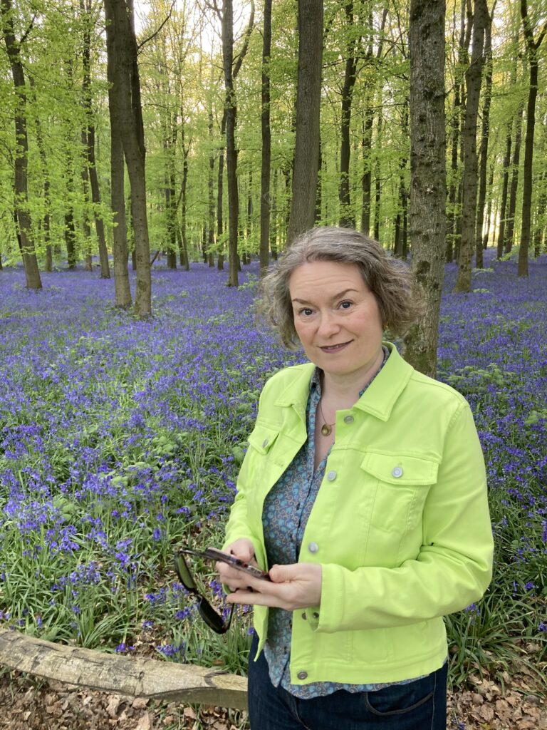jana in the woods looking up from her smartphone